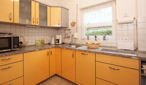 奥斯赛拜-屈隆斯博恩Ferienwohnung Muschelsucher的厨房配有黄色橱柜、水槽和窗户。