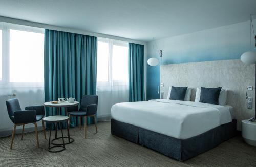 瓦讷瓦讷波特美居酒店的酒店客房带一张床、一张桌子和椅子