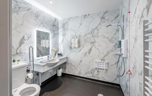 阿维莫尔High Range Holiday Apartments的一间带大理石墙壁、卫生间和水槽的浴室
