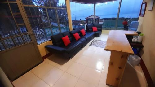 阿基塔尼亚Hospedaje Villa Isabel的客厅配有黑色沙发和红色枕头