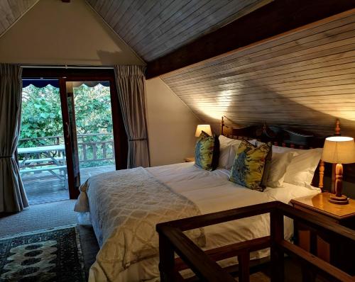 SanddrifTsitsikamma Gardens Self-Catering Cottages - Cottage #2的一间卧室设有一张带木制天花板的大床