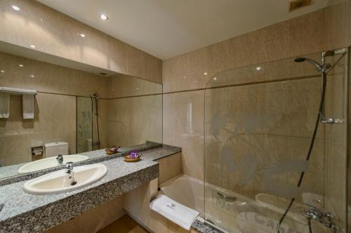 Ardón坎昆莱昂汽车旅馆的浴室配有水槽、淋浴和浴缸。