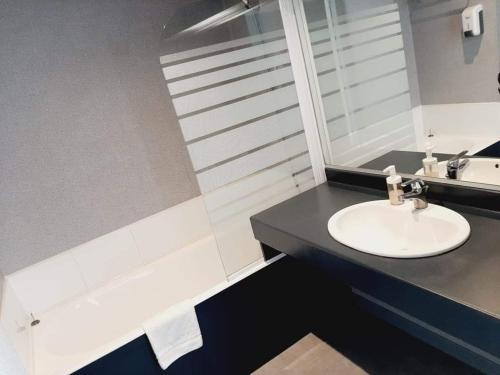 Sébazac-Concourès埃尔多拉多快捷酒店的浴室配有盥洗盆和浴缸。