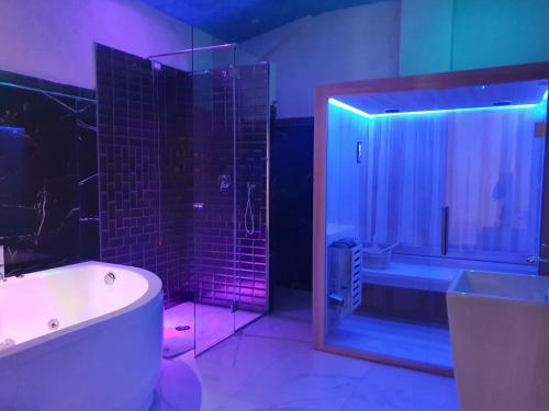 巴罗尼西Setteabbracci Suite & Apartments的浴室配有浴缸和紫色灯淋浴