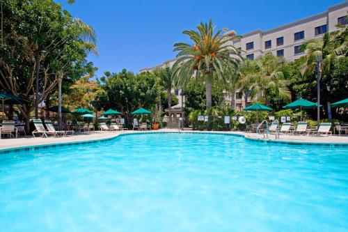 安纳海姆Sonesta ES Suites Anaheim Resort Area的酒店的大型游泳池配有椅子和遮阳伞