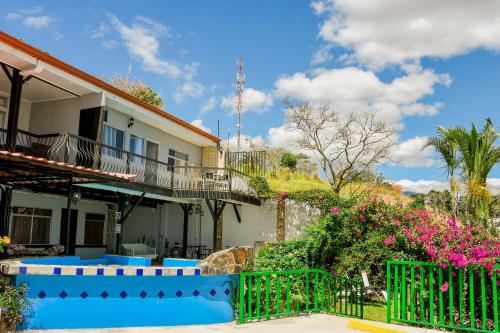 阿拉胡埃拉Loma Tranquila的一座带绿色围栏和鲜花的房子