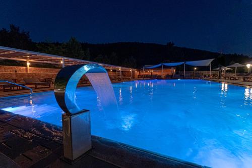 维蒂纳Nymfasia Resort的夜间大型蓝色游泳池