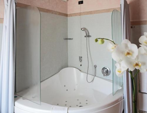 皮耶韦迪索利戈Hotel Contà Taste The Experience的带淋浴和鲜花的浴缸的浴室