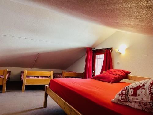 里蒙纽耶Les Menuires skis aux pieds的一间卧室配有一张带红色床单的床和一扇窗户。