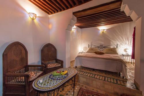 非斯达拉卜卡拉酒店的一间卧室配有一张床、两把椅子和一张桌子