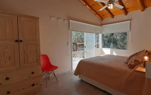 梅洛COSTA COM Departamentos de Montaña的一间卧室配有一张床和一张红色椅子