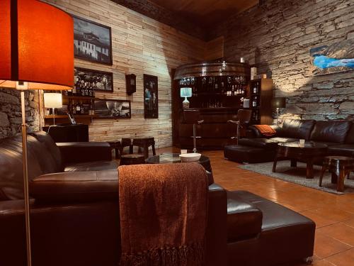 杜罗河畔瓦伦萨Quinta da Casa Cimeira, Guest House, Wines & Food的客厅配有皮革家具和砖墙