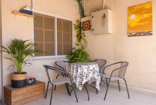 埃拉特Cosy Family Home & Garden in Eilat的种有植物的庭院里的桌椅