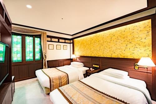 金泽金泽白鸟路山乐酒店的一间设有三张床和黄色墙壁的房间