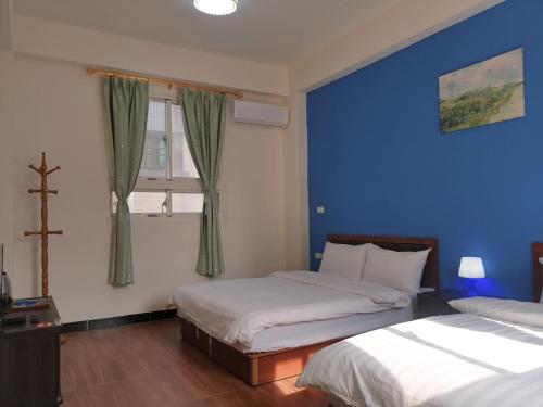 金宁乡绅士民宿的一间卧室设有两张床和蓝色的墙壁