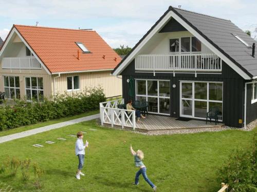 盖尔廷8 person holiday home in Gelting的两个人在房子的院子里玩飞盘