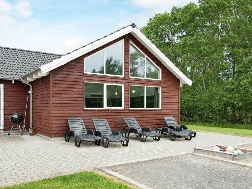 诺德堡18 person holiday home in Nordborg的坐在房子前面的一组椅子