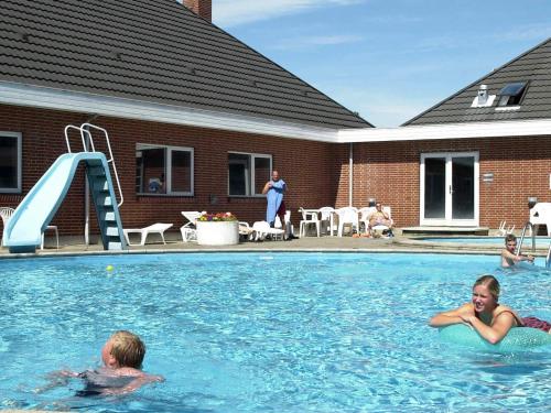 罗莫柯克比Three-Bedroom Holiday home in Rømø 39的两人在带滑梯的游泳池