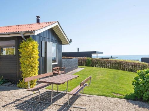 森讷比5 person holiday home in Juelsminde的一个小房子前面的野餐长凳