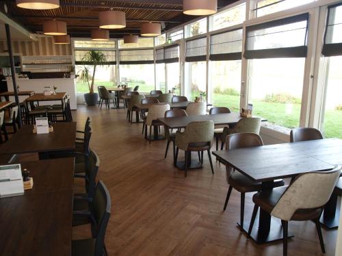 滨海卡特韦克赫伯格·维尔格勒根酒店的用餐室设有桌椅和窗户。