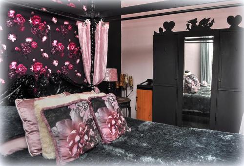 LlanegrynPeniarth arms的一间卧室配有一张带粉红色窗帘和镜子的床