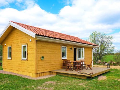 Sandhem4 person holiday home in SANDHEM的一座黄色的小房子,设有甲板和桌子