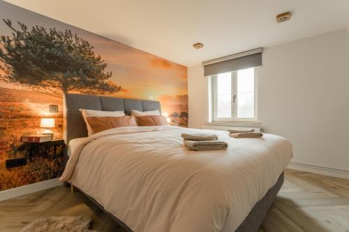 佩尔De Dommelhoeve的卧室配有一张大床,墙上挂有绘画作品