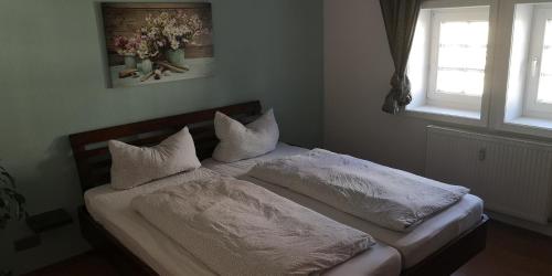WeimarFerienwohnung/Monteurwohnung im Herzen von Ahnatal的卧室内的一张带白色床单和枕头的床