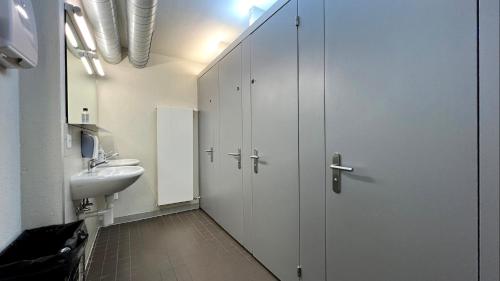 采尔马特采尔马特青年旅舍的一间带卫生间、水槽和白色橱柜的浴室