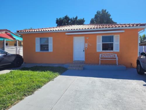 迈阿密Welcome Heart and Reliable Heart Vacation Houses的一座橙色的小房子,前面设有长凳