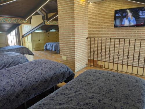 拉耶斯Villa El Rosal del Pozo, a 5 minutos de Puy du Fou的一间设有三张床的客房,砖墙上设有一台电视