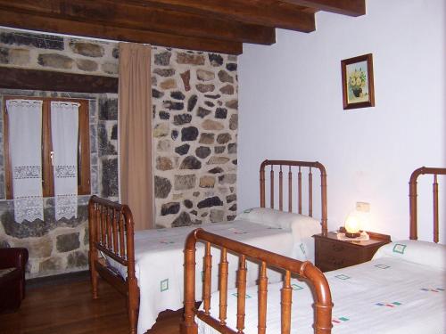 莱昆韦里Casa Rural Barbonea的一间卧室设有两张床和石墙