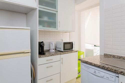 里斯本Estrela Garden Apartment的厨房配有白色橱柜和微波炉