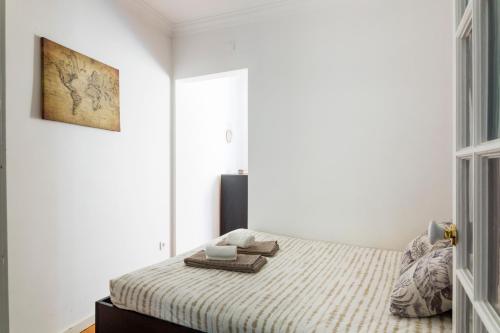 里斯本Estrela Garden Apartment的白色卧室配有一张带毯子的床