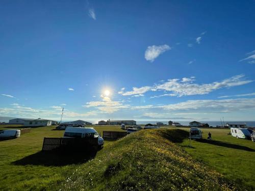 BakkafjörðurNorthEast Guesthouse的草地上,有汽车停在田野里