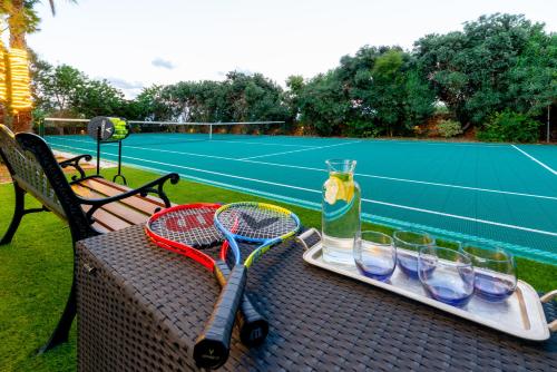 沙拉ALTO Beyond的网球场上配有带网球拍和玻璃杯的桌子