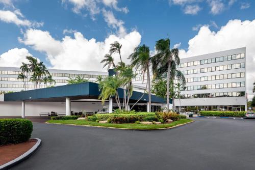 迈阿密Sonesta Miami Airport的一座白色的大建筑,前面有棕榈树