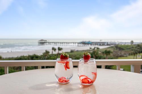 可可比奇Cocoa Beach Towers的餐桌上享有海滩美景,供应2杯鸡尾酒