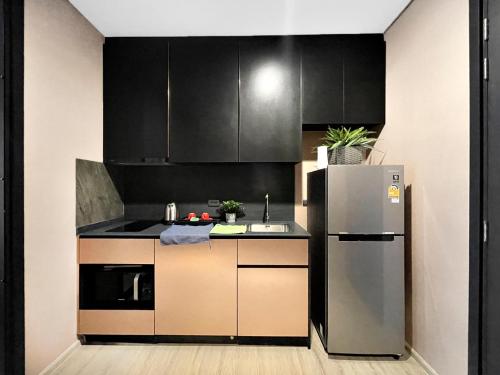 芭堤雅市中心Edge Central Pattaya by J&P的厨房配有黑色橱柜和不锈钢冰箱