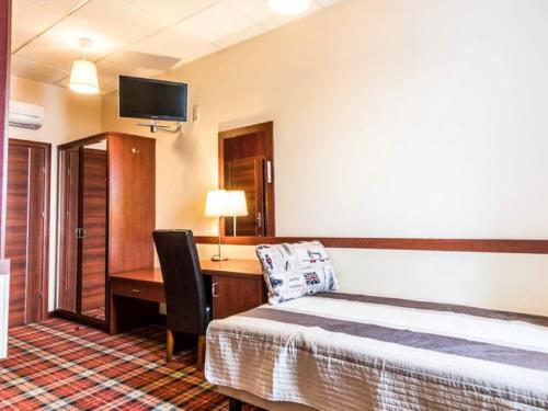弗罗茨瓦夫Hotel Stara Garbarnia的酒店客房配有一张床、一张书桌和一台电视。
