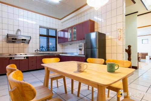 关山镇伯特利民宿的厨房配有木桌、椅子和冰箱。