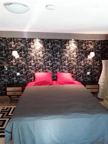 ChâteauvieuxGite les Cigales的一间卧室配有一张大床,提供红色枕头和黑色壁纸