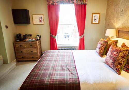 温彻斯特维克汉姆阿姆斯酒店的一间卧室配有一张带红色窗帘的床和一扇窗户