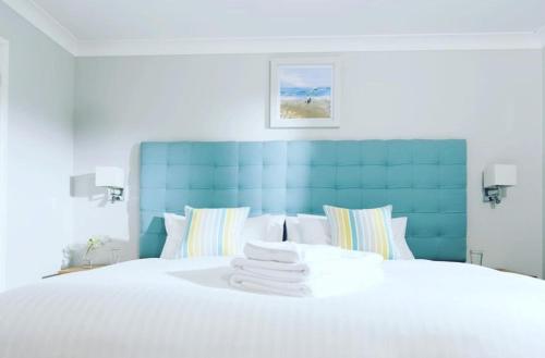 帕兹托Padstow 2 bedroom Lodge at Retallack Resort的一间卧室配有一张白色的床和蓝色床头板