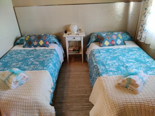 San Cristóbal de Segovia圣克里斯托瓦尔希古恩纳斯度假屋的一间卧室配有两张床和一张桌子及床头柜