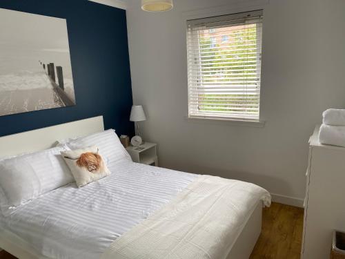 爱丁堡爱丁堡海滨公寓的卧室配有白色的床,枕头上有猫