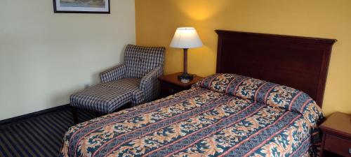 Ashford阿什福德汽车旅馆的配有一张床和一把椅子的酒店客房