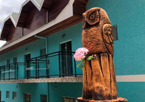 坎波斯杜若尔当Pousada Alpes Azul的一座建筑前的猫头鹰雕像,上面有花