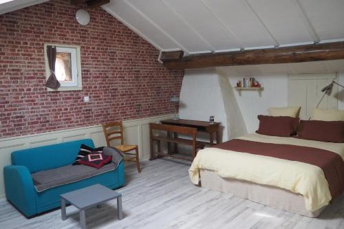 ArchettesChambres d'hôtes du Ruisseau d'Argent的一间卧室配有床、沙发和砖墙
