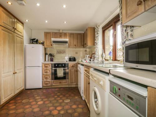 MorlandPond End Cottage的厨房配有木制橱柜和白色冰箱。